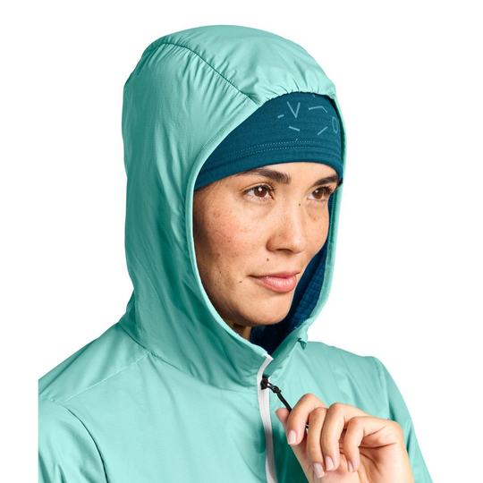 Ladiz Hybrid Jacket W worn by a woman with hood up, showcasing windproof inserts and lightweight Merino material.