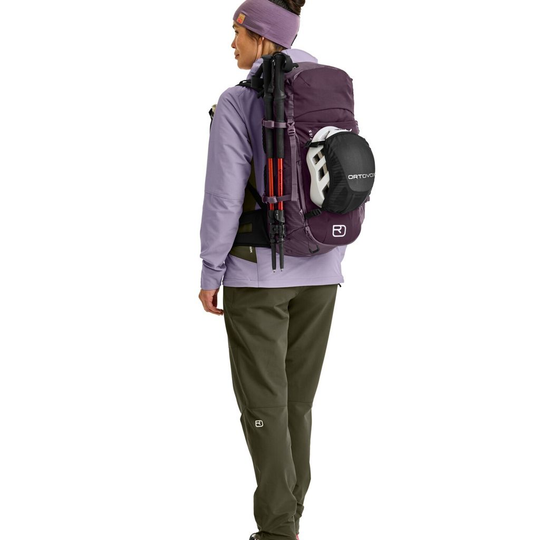 Traverse 28 S backpack worn by a person, showing its versatile and eco-friendly design with helmet net and pole attachments.