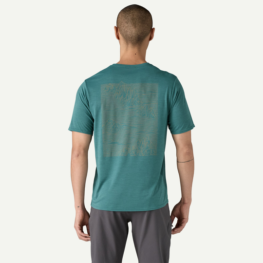 M's Cap Cool Daily Graphic Shirt in teal, featuring mountain graphic on the back, short sleeves, and designed for versatility and comfort.