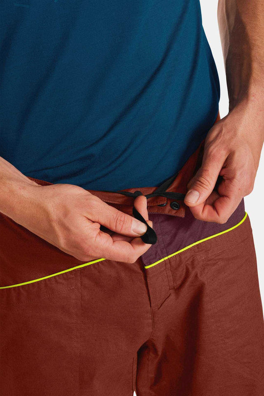 Valbon Pants M being adjusted at waist, featuring organic cotton and hemp fabric, ideal for climbing.