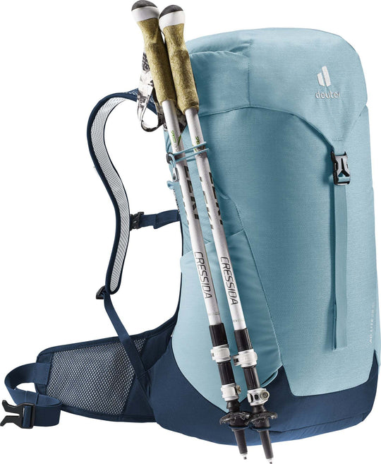 Light blue Deuter AC Lite 28 SL hiking backpack with trekking poles attached, showcasing lightweight design and Aircomfort ventilation system.