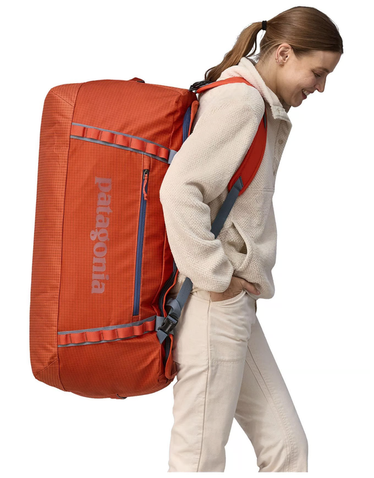 Black Hole Duffel 100L in use, showing removable shoulder straps and compact design.