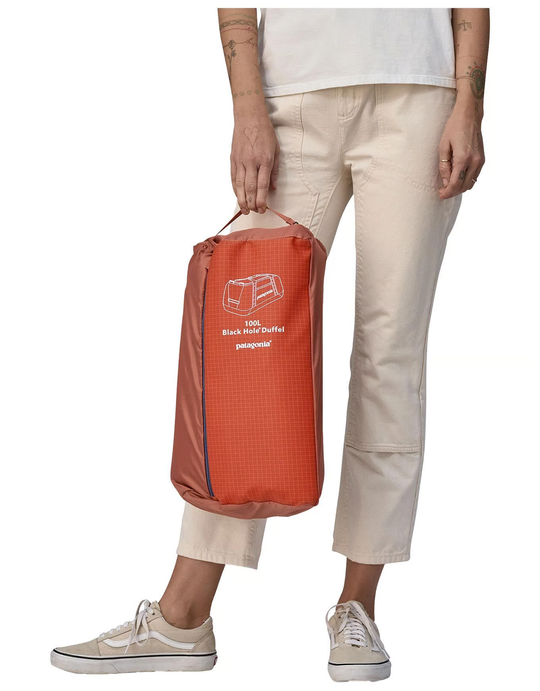 Compact Black Hole Duffel 100L bag held by person, showcasing portability and storage convenience.