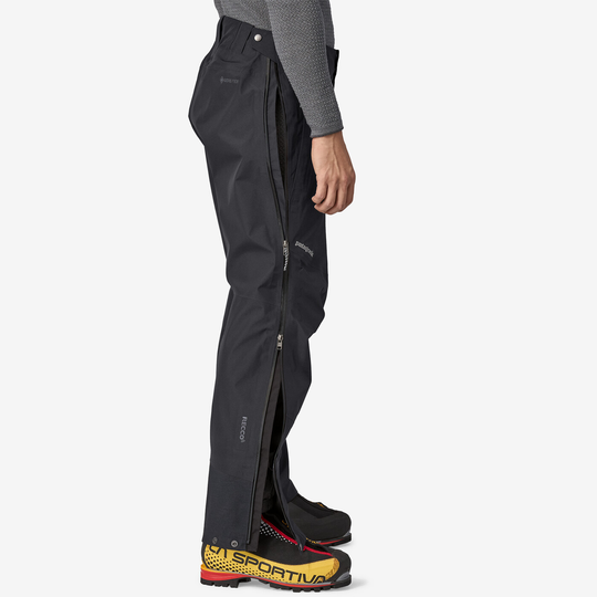 Men's black Triolet Pants with full-length side zips, made from recycled 3-layer GORE-TEX, PFC-free, featuring RECCO® reflector and reinforced cuffs.