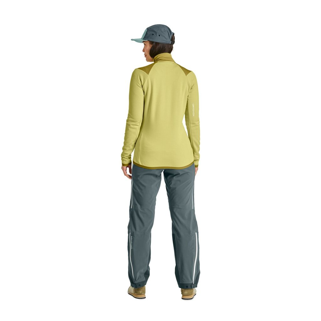 Woman wearing Fleece Grid Jacket in mountain setting, showcasing technical fleece with Merino wool for warmth and breathability.