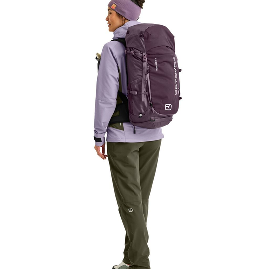 Traversal 38 S backpack in purple on person, ideal for multi-day alpine hikes.