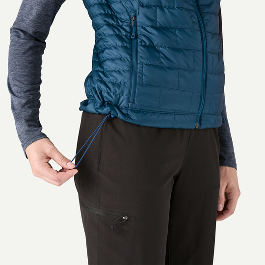 W's Nano Puff Vest in blue, featuring lightweight PrimaLoft Gold Insulation and ripstop fabric, shown with adjustable hem cord detail.