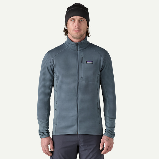 R1 Jkt men's lightweight breathable technical jacket in blue with zipper pockets and elastic cuffs.