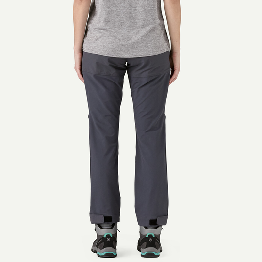 Back view of a person wearing gray Terravia Peak Pants, showcasing adjustable reinforced ankle cuffs, suitable for hiking boots.