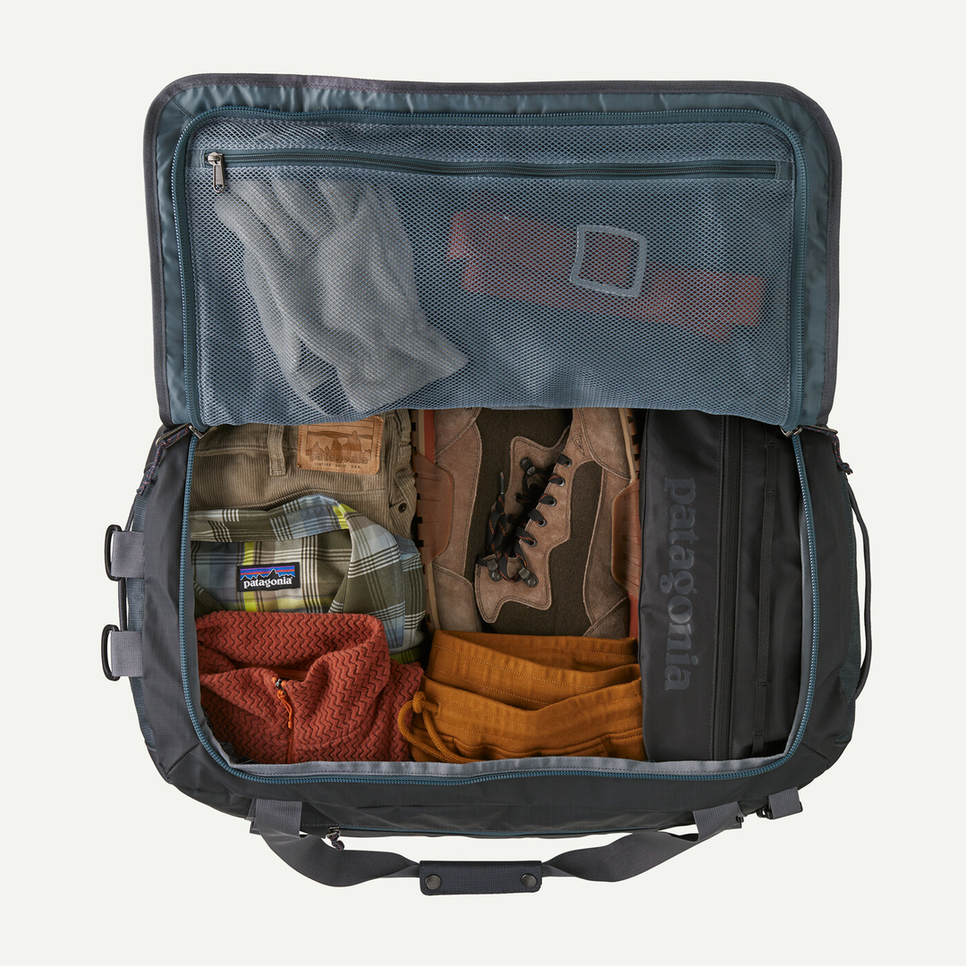 Black Hole Duffel 55L open with clothes and travel gear inside.