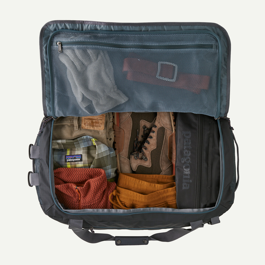 Black Hole Duffel 55L open with clothes and travel gear inside.