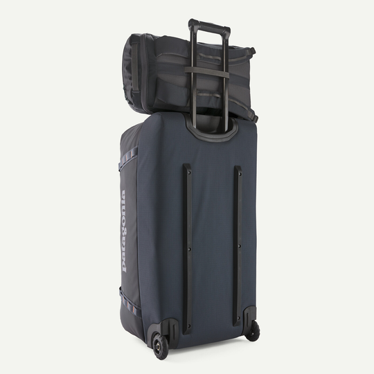 Black Hole Pack 25L backpack attached to trolley bag, showcasing durable recycled polyester fabric with TPU film.