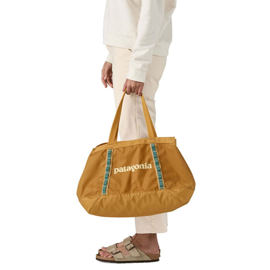 25L Black Hole Tote bag being carried, made from recycled materials, Fair Trade Certified.