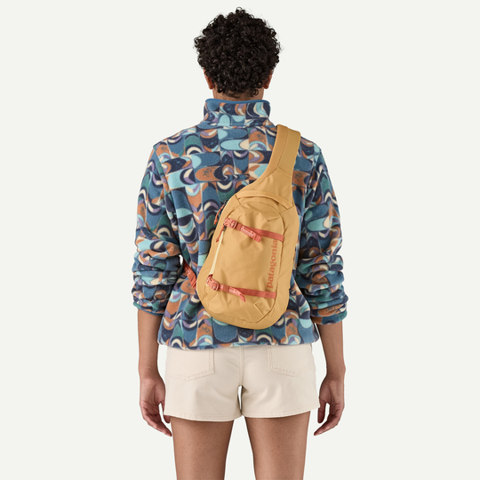 Atom Sling 8L monospalla in poliestere riciclato su persona, design ergonomico, tasca frontale zip.