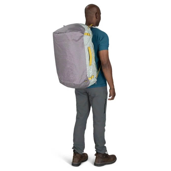 Transporter 65 duffel bag worn as a backpack by a person, showcasing its robust weather-resistant design and convenient portability.