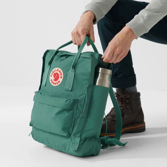 Zaino Kånken in resistente tessuto Vinylon verde con tasche multiple e cerniera anteriore, adatto per uso scolastico e trekking.