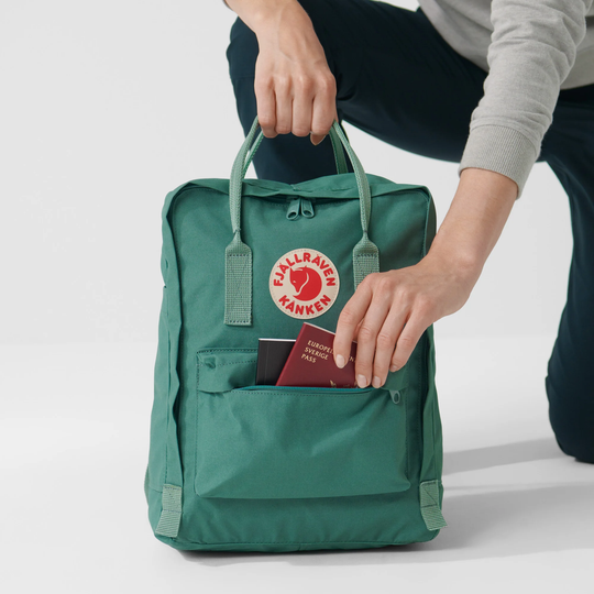 Zaino Kånken verde con tasca frontale aperta, resistente tessuto Vinylon, logo riflettente.