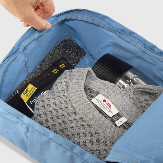Kånken Rainbow backpack interior with sweater, water bottle, and packed items.