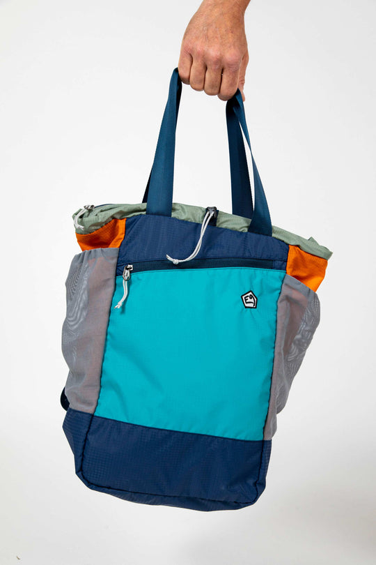 Multi-colored technical backpack held by hand.