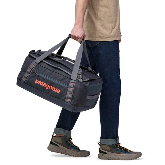 Black Hole Duffel 40L being carried, showcasing durable straps and compact size.