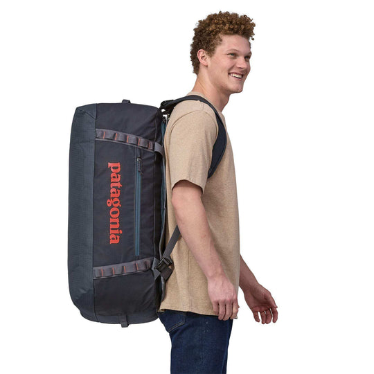 Black Hole Duffel 70L worn as a backpack by a person, showcasing its ergonomic design and spacious capacity.