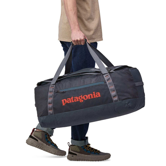 Black Hole Duffel 70L being carried, featuring durable recycled materials and ergonomic straps.