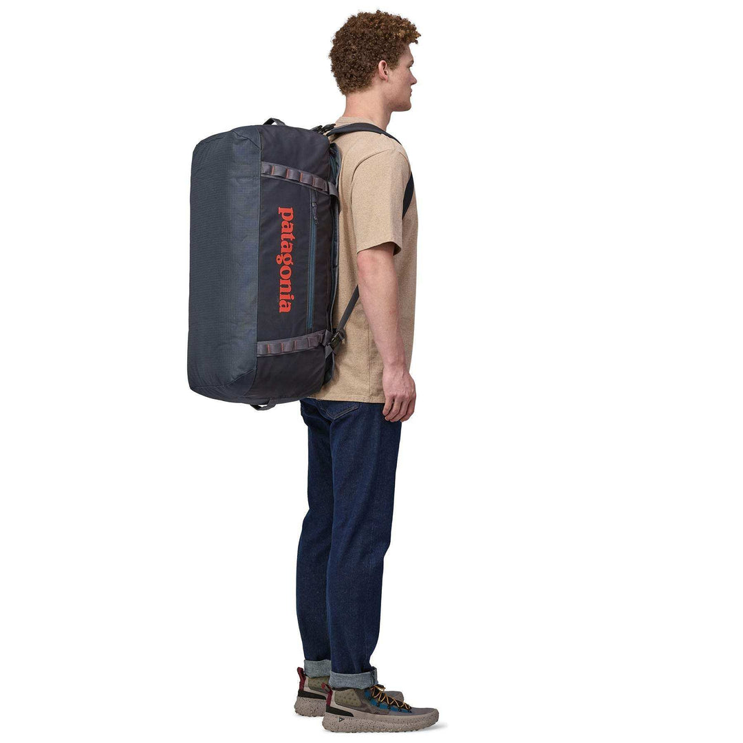 Man carrying Black Hole Duffel 70L backpack with ergonomic straps.