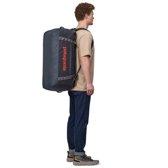 Man carrying Black Hole Duffel 70L backpack with ergonomic straps.