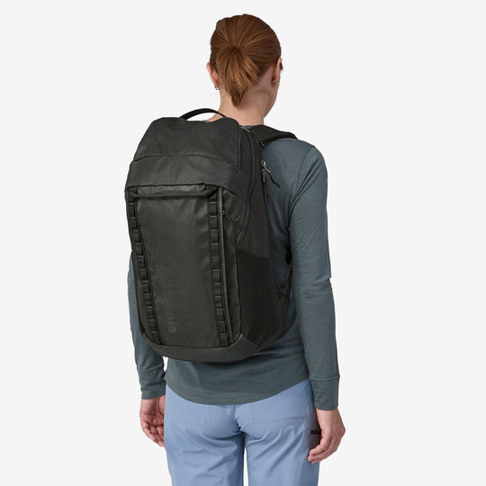 Black Hole Pack 32L worn by person, durable recycled polyester material with water-repellent finish, spacious storage options.