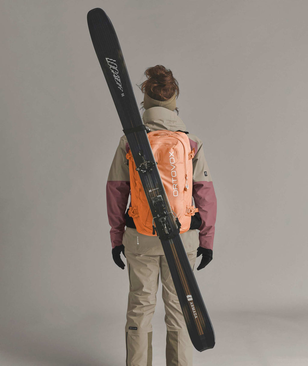 Ortovox Haute Route 30 S Faded Tangerine, indossato con sci fissati in diagonale