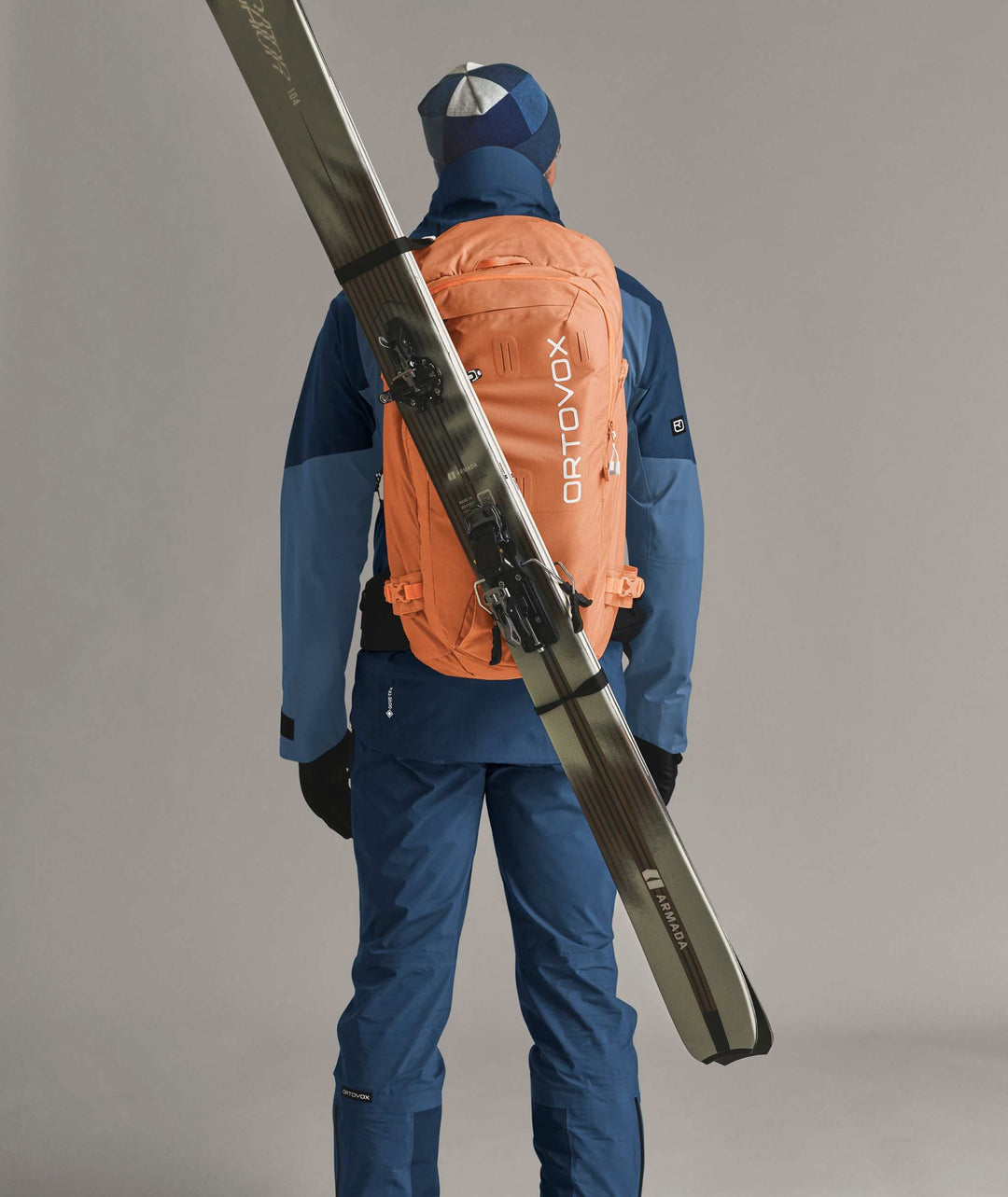 Ortovox Haute Route 40 Faded Tangerine, indossato con sci fissati in diagonale