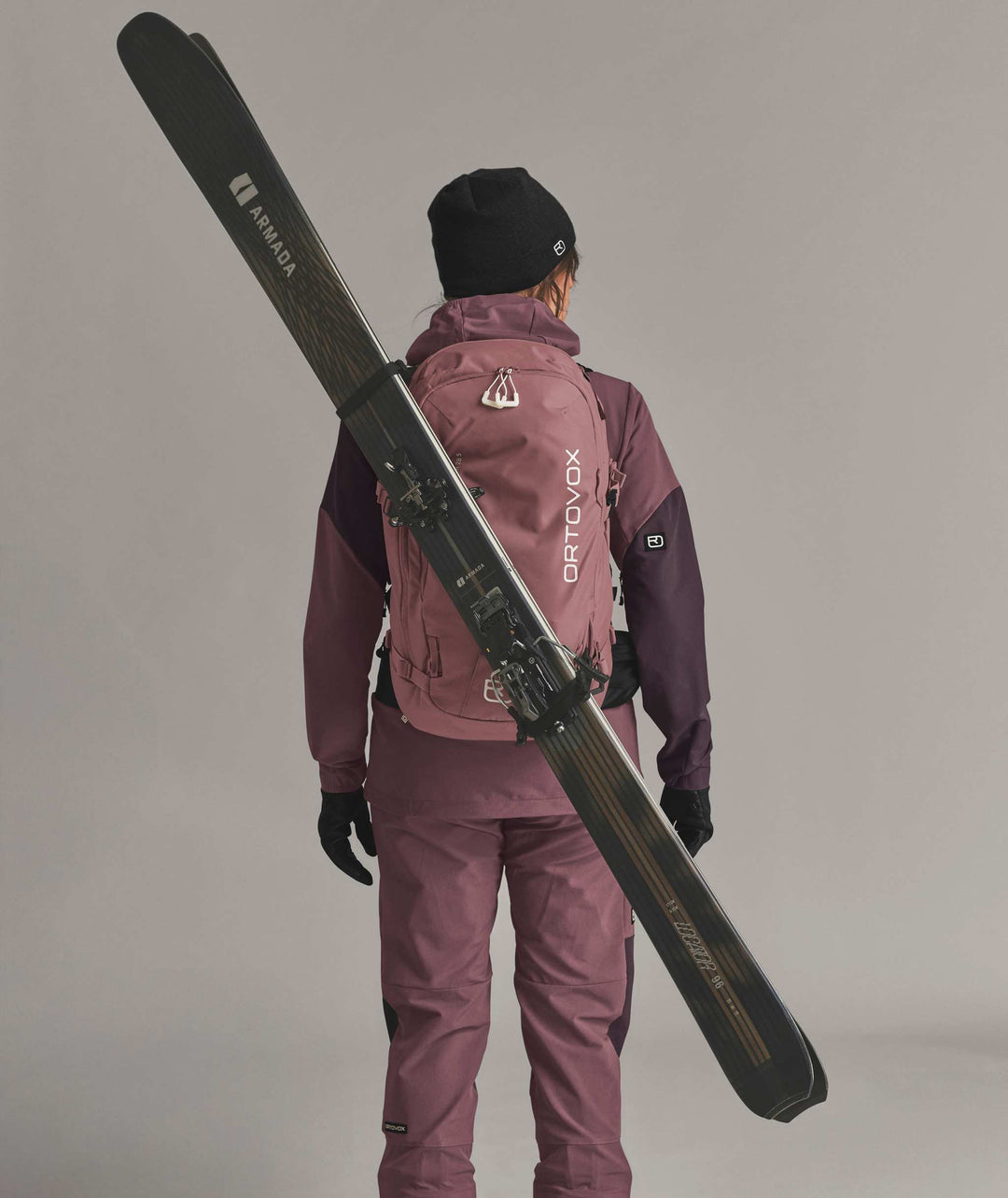 Ortovox Venet Tour 28 S Dusk Rose, indossato con sci fissati in diagonale