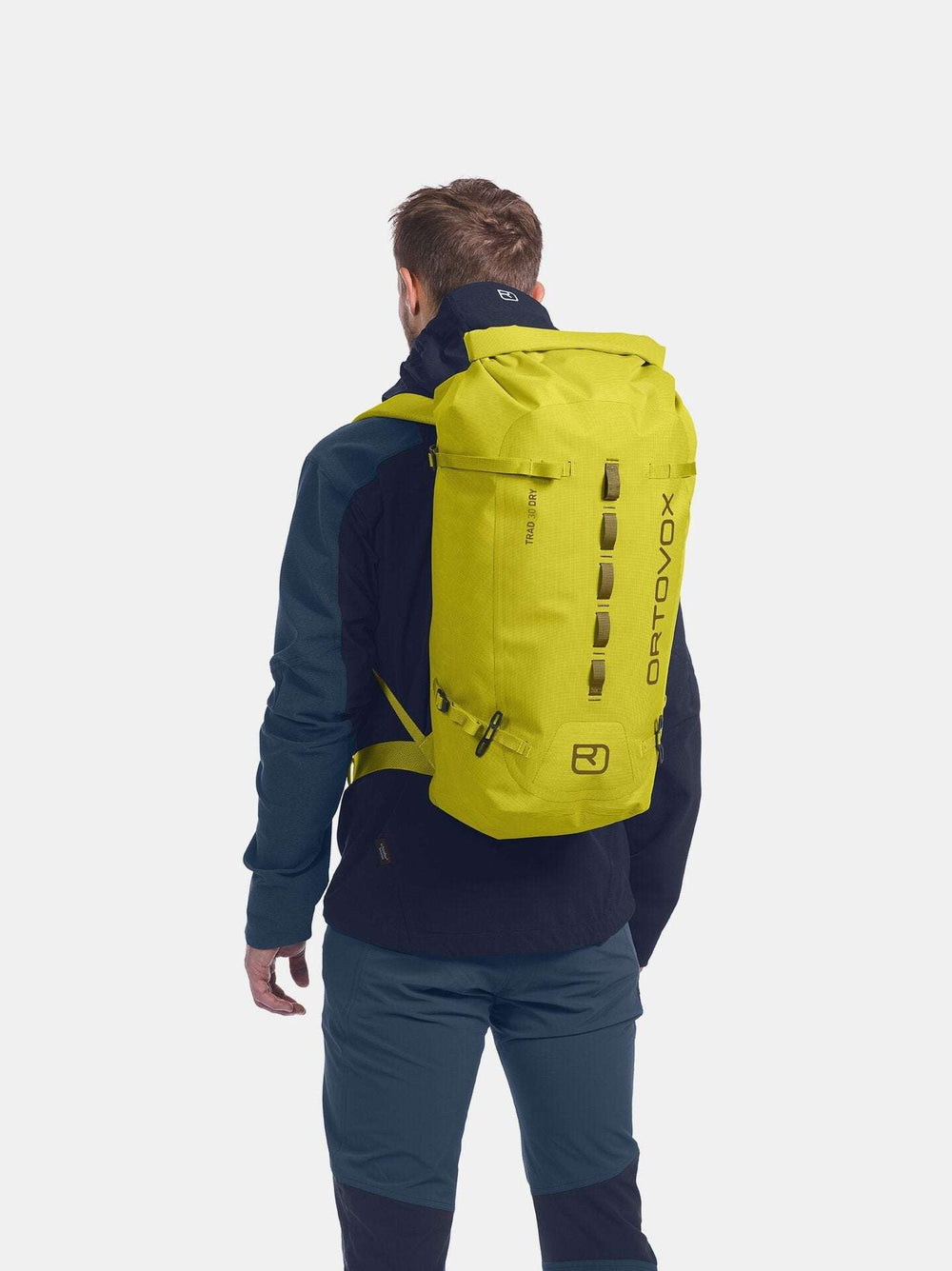 Weather-resistant Trad 30 Dry climbing backpack in yellow, worn by a person.