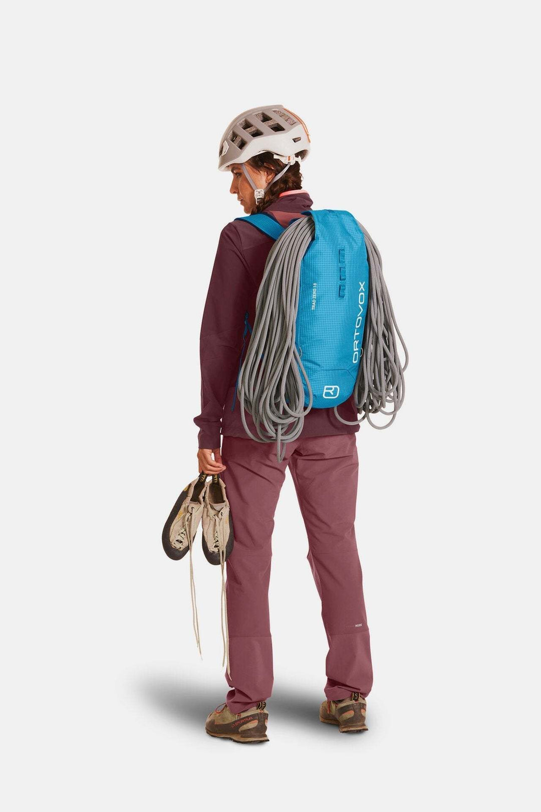 Lightweight Trad Zero 18 alpine climbing backpack, blue with rope attachment, worn by hiker.